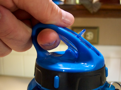 Finger inside the bottle's handle touches the closed spout