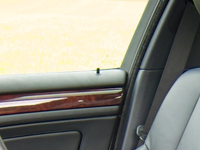 Inside view of a car's front door with lock pin sticking out from the top of the inside door cover.