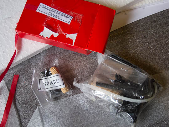 Two plastic bags contain numerous mounting hardware parts like screws, etc. These bags are contained in the small, red cardboard box that the ribbon is attached to.