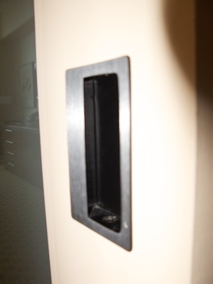 Recessed door handle partially covered with metal front plate