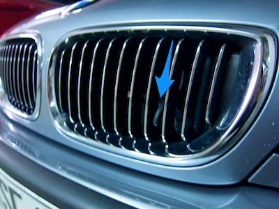 BMW car's front grille with retracted handle somewhat hidden between the grill's fins