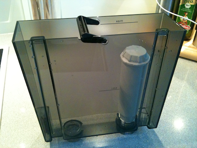 Water tank from a coffee maker with a white filter cartridge mounted in its inside