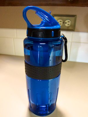 Water bottle sitting on a counter top, showing handle loop, closed spout, and carrying shackle