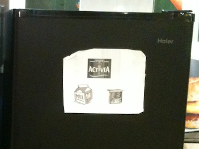 A sheet of paper is affixed to the fridge with the opaque door, showing the Activia brand symbol, a generic milk carton sketch, and an Activia yoghurt cup. All in glorious gray-and-white, and rather fuzzy at the edges.