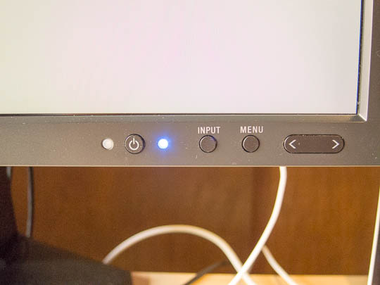 Several hardware buttons are embedded in the bottom right corner of the computer monitor's bevel. These are used for interacting with the device's on-screen configuration menus. The power LED is to the right of the power button, and it glows blue when the screen is lit.